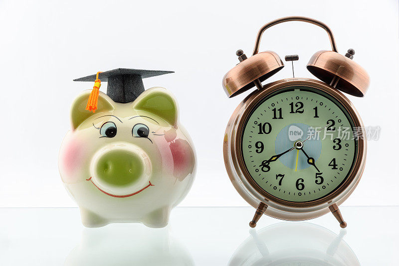 存钱教育和研究生学习方案概念:黑色毕业帽/帽子上的存钱罐和模拟时钟，描绘了长期投资儿童教育，以确保他们的未来。